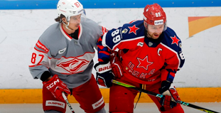 Два хоккеиста в разной форме на льду во время матча; один в красной, другой в серой экипировке